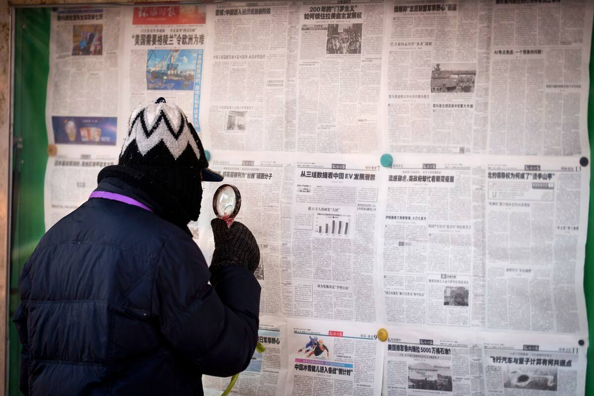 Un hombre lee periódicos colgados en un tablón de anuncios en Pekín, China, el viernes 9 de enero de 2026. (Foto AP/Vincent Thian)