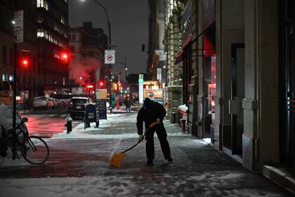 Un hombre limpia la nieve de una vereda en New York, este martes 16 de enero de 2024. (Photo by ANGELA WEISS / AFP)