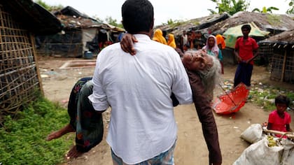 Un hombre lleva a una mujer refugiada de Rohingya desde la orilla luego de cruzar la frontera de Bangladesh-Myanmar en un barco a través de la bahía de Bengala