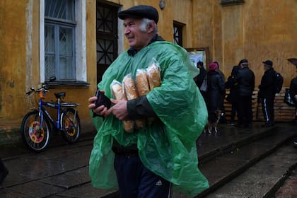 Un hombre lleva un pasaporte ucraniano y pan después de recibirlo en un centro de ayuda humanitaria en Kramatorsk, Ucrania, el 26 de octubre de 2022. (Foto AP/Andriy Andriyenko)