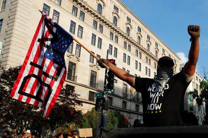 Un hombre marcha en Washington con una bandera con las siglas del movimiento internacional "Black Lives Matter"