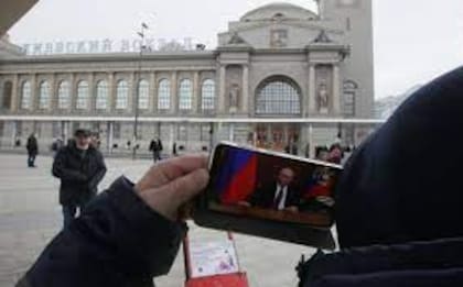 Un hombre mira en el teléfono móvil un mensaje del presidente Vladimir Putin, frente a la estación de trenes de Kievskaya, en Moscú