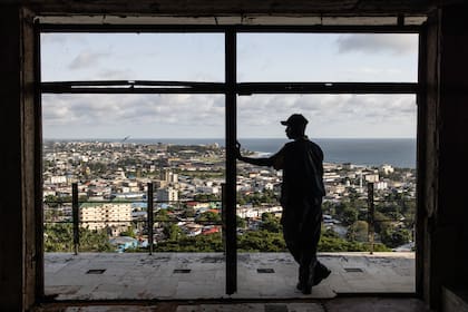 Un hombre mira la ciudad desde la ventana de un dormitorio antiguo en el hotel Ducor en ruinas en Monrovia