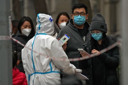 Un hombre muestra su código QR de control de salud mientras él y otras personas hacen fila para hacerse pruebas de rutina de COVID-19 en Beijing, China, el 24 de noviembre de 2022