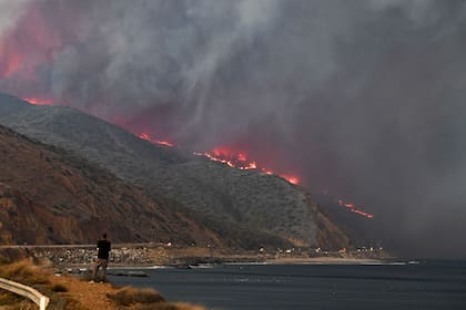 Un hombre observa como el incendio de Woolsey se acerca a la costa del Pacífico, cerca de Malibú, California