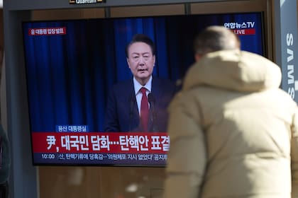 Un hombre observa una pantalla de televisión que muestra la retransmisión en directo del anuncio del presidente surcoreano Yoon Suk Yeol en la estación de ferrocarril de Seúl, Corea del Sur, el sábado 7 de diciembre de 2024. (Foto AP/Lee Jin-man)