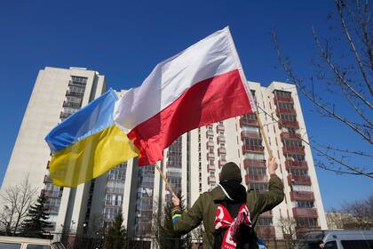 Un hombre ondea banderas de Polonia y Ucrania durante una manifestación delante de un edificio que alberga a diplomáticos rusos en Varsovia el 13 de marzo del 2022. (AP Foto/Czarek Sokolowski)