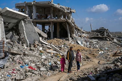 Un hombre palestino y dos niñas observan los escombros de viviendas destruidas por la ofensiva aérea y terrestre del ejército de Israel contra Hamás en el campamento para refugiados Bureij, en el centro de la Franja de Gaza, el lunes 27 de febrero de 2025
