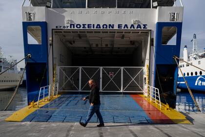 Un hombre pasa junto a la rampa de entrada a un transbordador amarrado en el puerto de Pireo durante una huelga general de 24 horas, el 16 de marzo de 2023. (AP Foto/Petros Giannakouris)