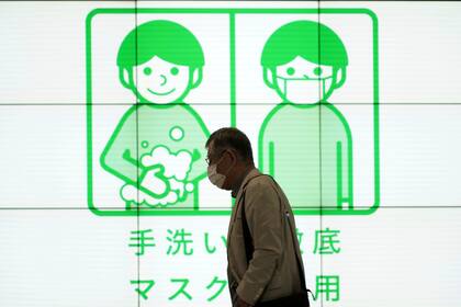Un hombre pasa junto a un cartel de concienciación sobre el uso de mascarillas y lavado de manos para ayudar a frenar los contagios de coronavirus, el miércoles de 29 septiembre de 2021, en Tokio. (AP Foto/Eugene Hoshiko)