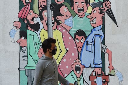 Un hombre pasa junto a un mural que muestra a personas de pie cerca unas de otras para crear conciencia sobre el mantenimiento del distanciamiento social y el uso de máscaras, en Mumbai, la India, el 2 de marzo de 2021