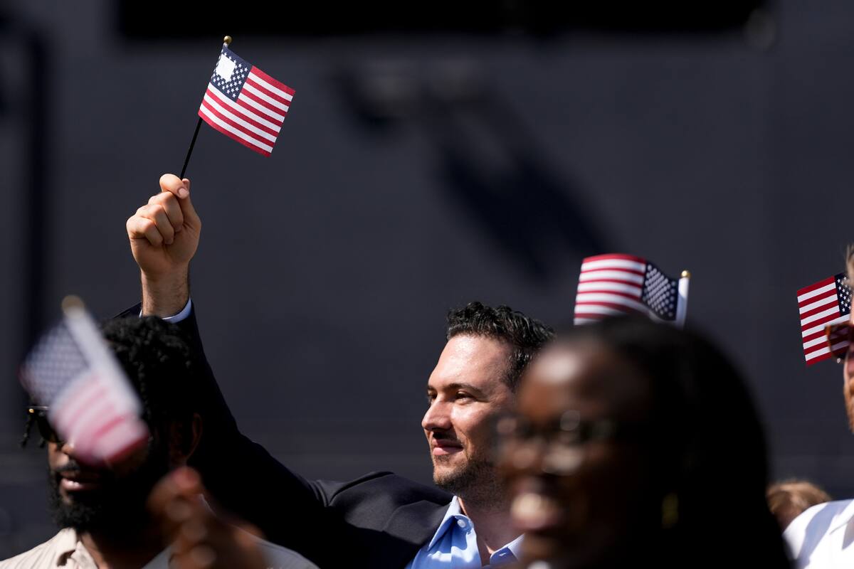 Un hombre, que forma parte de un grupo de 50 nuevos ciudadanos estadounidenses oriundos de 25 países diferentes, ondea una bandera de Estados Unidos durante una ceremonia de naturalización antes del partido de los Padres de San Diego ante los Mellizos de Minnesota, en Petco Park, el miércoles 21 de agosto de 2024, en San Diego. (AP Foto/Gregory Bull)
