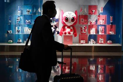 Un hombre que llevaba una máscara protectora pasa por la Tienda Olímpica Oficial de Tokio en el Aeropuerto Internacional de Tokio Haneda.
