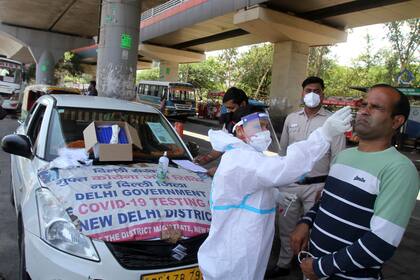 Un hombre reacciona mientras una trabajadora sanitaria con un traje de protección le toma una muestra nasal para una prueba de COVID-19 en Nueva Delhi, India, el sábado 22 de mayo de 2021. (AP Foto/Satish Sharma)