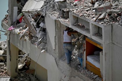 A man searches through the rubble of a collapsed building trying to recover his belongings after an earthquake in Catia La Mar