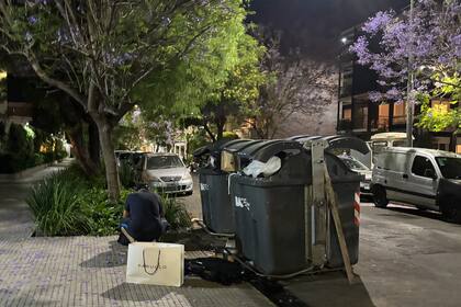 Un hombre revisa residuos junto a contenedores desbordados en una calle en Barrio Parque
