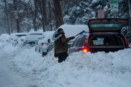 Un hombre sacando la nieve de su auto en Nueva Jersey