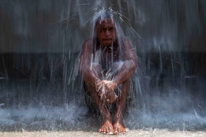 Un hombre se refresca bajo una fuente de agua en el Parque Madureira en medio de una ola de calor, el miércoles 15 de noviembre de 2023, en Río de Janeiro, Brasil. (AP Foto/Bruna Prado)