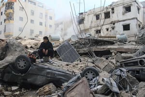 Un hombre se sienta sobre los escombros de un edificio que fue atacado por un bombardeo aéreo israelí