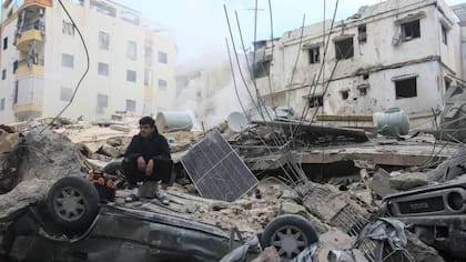Un hombre se sienta sobre los escombros de un edificio que fue atacado por un bombardeo aéreo israelí