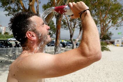 Un hombre se vuelca agua en la cara para refrescarse en la playa Ricanto en Ajaccio, en la isla francesa de Córcega, el 19 de julio de 2023, mientras Europa es golpeada por una importante ola de calor.