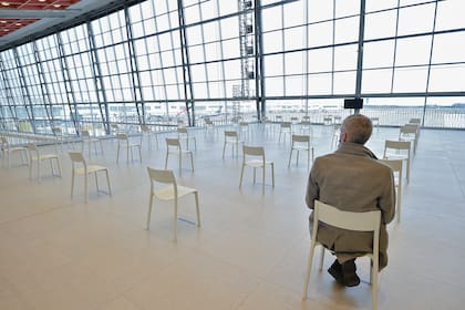 Un hombre sentado en una zona de descanso antes de recibir una inyección de la vacuna Covid-19 el día de la inauguración del centro de vacunación en el aeropuerto Zaventem Skyhall de Bruselas, en Zaventem, el 22 de febrero de 2021