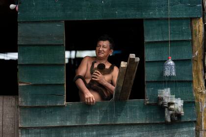 Un hombre sostiene a su mono mascota mientras mira desde su casa en el barrio Belén de Iquitos, Perú, el sábado 25 de mayo de 2024. La comunidad indígena en el corazón de la Amazonía peruana conocida como la "Venecia de la Selva" organiza el Festival de Cine Flotante Mayuna, que celebra los bosques tropicales. (Foto AP/Rodrigo Abd)