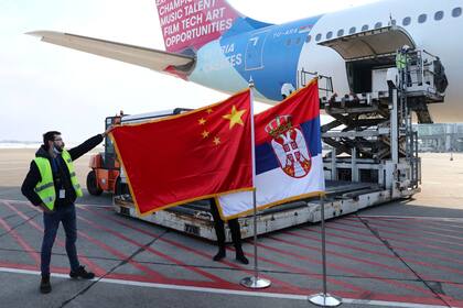 Un hombre sostiene la bandera de China junto a la bandera de Serbia mientras un avión que transporta un millón de dosis de vacunas del Grupo Nacional Biotec de China (CNBG) de Sinopharm para la enfermedad del coronavirus (COVID-19) llega al aeropuerto Nikola Tesla en Belgrado, Serbia, el 16 de enero
