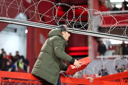 Un hombre sostiene un asiento arrojado por los hinchas de la U. de Chile en el estadio de Independiente