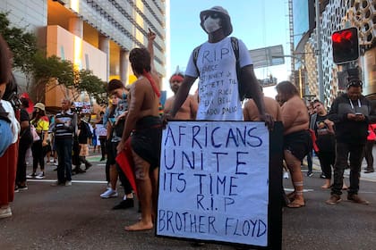 Un hombre sostiene un cartel con miles de personas que marchaban durante una protesta de Black Lives Matter en Brisbane, Australia