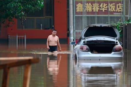 Un hombre vadea una carretera inundada tras las fuertes lluvias en Zhuozhou, en la provincia septentrional china de Hebei, el 2 de agosto de 2023. (Foto de Jade Gao / AFP)