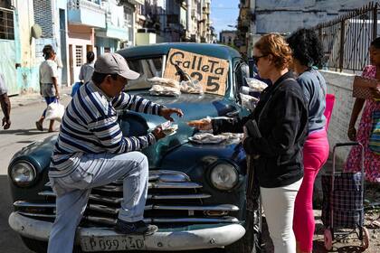 Un hombre vende galletas en un viejo coche estadounidense en La Habana el 20 de diciembre de 2023