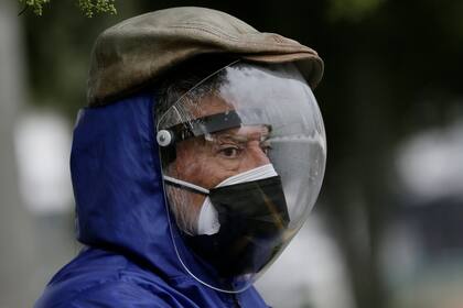 Un hombre vestido con un protector facial completo y una máscara doble para evitar el contagio del COVID-19 espera su turno para ser vacunado, afuera de un centro de vacunación del Instituto del Seguro Social en Quito, Ecuador, el jueves 6 de mayo de 2021. (AP Foto/Dolores Ochoa)