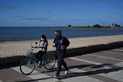 Un hombre y su hija usan máscaras mientras hacen ejercicio a lo largo de la Rambla de Montevideo, el 14 de mayo de 2020, en medio de la pandemia de coronavirus