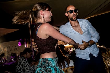 Un hombre y una mujer bailan en la arena en un restaurante al aire libre de una playa en Fregene, cerca de Roma, el 14 de agosto de 2020