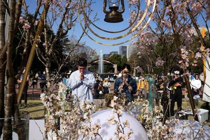 Un hombre y una mujer rezan tras depositar flores en un monumento para conmemorar el 12mo aniversario de un masivo sismo, tsunami y un desastre nuclear, en el Parque Hibiya, en Tokio, el 11 de marzo de 2023. (AP Foto/Hiro Komae)