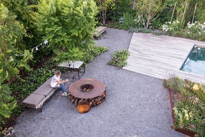 Un jardín sin césped, con binder como solado. El fogón es de chapa y el centro es desmontable. La leña se guarda debajo.