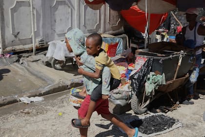 Un joven carga a un niño sobre su espalda en una escuela que actualmente sirve como albergue para quienes huyen de la violencia de las pandillas, el lunes 14 de abril de 2025, en Puerto Príncipe, Haití.