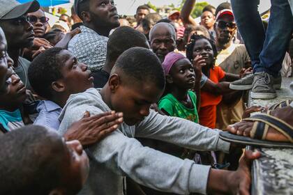 Un joven llora mientras espera que le entreguen arroz que es distribuido entre los habitantes de Les Cayes, Haití, el lunes 16 de agosto de 2021, dos días después de que un sismo de magnitud 7,2 sacudió el suroeste del país. (AP Foto/Joseph Odelyn)