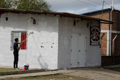 Un joven pinta el frente de su casa, que ahora será blanco liso, sin insignias políticas