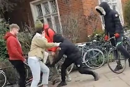 Un ladrón tironea de la bicicleta para llevársela, ante la resistencia de tres vecinos en el paque Victoria, en Londres, el domingo por la tarde