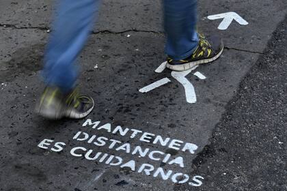 Un letrero en la vereda recuerda a las personas que deben mantener una distancia prudencial entre sí debido a la pandemia de coronavirus, en la avenida Corrientes en Buenos Aires, el 18 de mayo de 2020