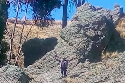 Un lugareño se para delante de la piedra que aseguran se parece a Homero Simpson
