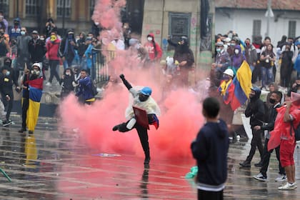 Un manifestante antigubernamental devuelve un bote de gas lacrimógeno a la policía durante los enfrentamientos en Bogotá, Colombia, el miércoles 5 de mayo de 2021. Las protestas que comenzaron la semana pasada por una propuesta de reforma tributaria continúan a pesar de que el presidente Iván Duque retiró el plan tributario el domingo 2 de mayo. (AP Foto/ Fernando Vergara)