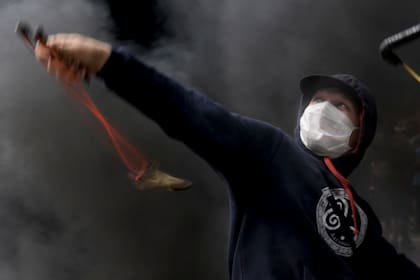 Un manifestante apunta su honda durante la protesta frente al Congreso mientras los legisladores se preparan para votar la ley para ratificar el acuerdo del gobierno con el Fondo Monetario Internacional