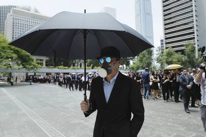 Un manifestante, con máscara y paraguas