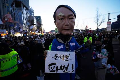 Un manifestante con una máscara del presidente surcoreano Yoon Suk Yeol, quien se encuentra en proceso de juicio político, durante una manifestación para exigir la renuncia de Yoon, el sábado 29 de marzo de 2025, en Seúl, Corea del Sur. La pancarta dice: "Destituyan a Yoon Suk Yeol". (AP Foto/Ahn Young-joon)