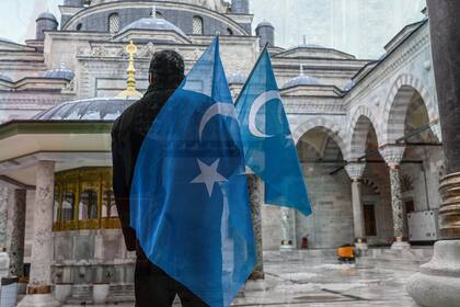 Un manifestante de la comunidad uigur que vive en Turquía se encuentra con banderas en la mezquita de Beyazit durante una protesta contra la visita del ministro de Relaciones Exteriores de China a Turquía, en Estambul el 25 de marzo de 2021