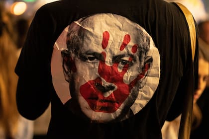 Un manifestante en Tel Aviv lleva el sábado una camiseta con el primer ministro israelí, Benjamin Netanyahu, con la mano ensangrentada en el rostro durante una manifestación contra el gobierno y por la liberación de los rehenes retenidos en la Franja de Gaza por el grupo militante Hamas.. Photo: Gaby Schutze/ZUMA Press Wire/dpa