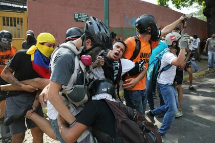 Un manifestante es llevado después de que fue afectado por gas lacrimógeno lanzado por las fuerzas de seguridad, fuera de la base aérea de La Carlota durante los enfrentamientos entre las dos partes en Caracas